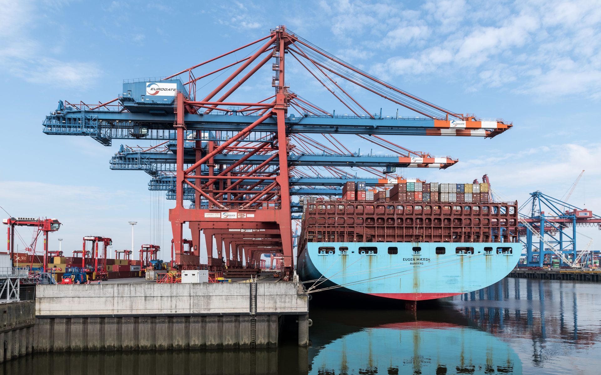 Navio porta-contentores atracado num terminal, com guindastes de pórtico a operar