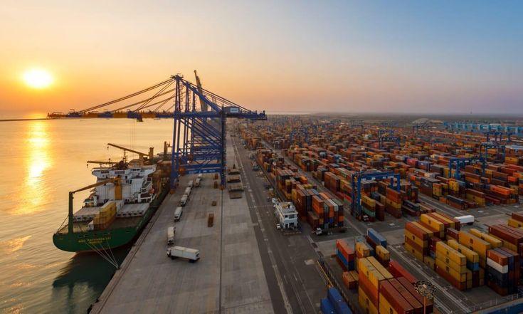Terminal portuário ao pôr do sol, com contentores e um navio atracado